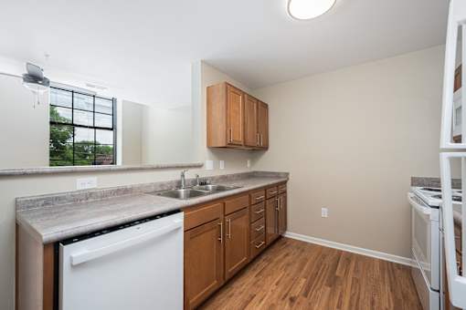 A kitchen with wooden cabinets and a white dishwasher.