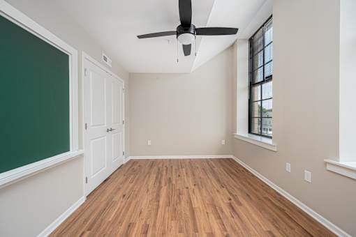 A room with a ceiling fan and wooden flooring.