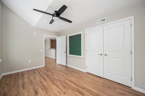 A room with a ceiling fan and wooden floors.