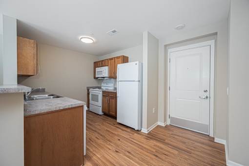 A kitchen with a white refrigerator and wooden cabinets.