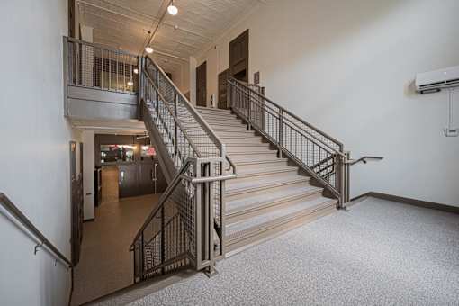 A staircase with a metal railing and a carpeted floor.