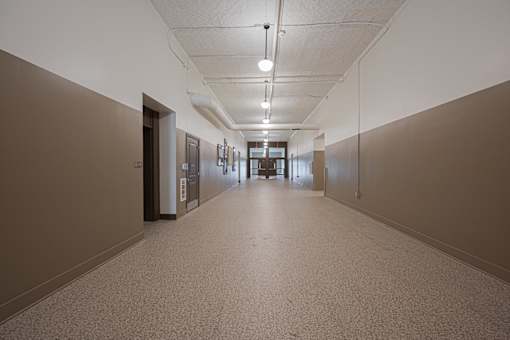 A long hallway with doors on both sides and a light on the ceiling.