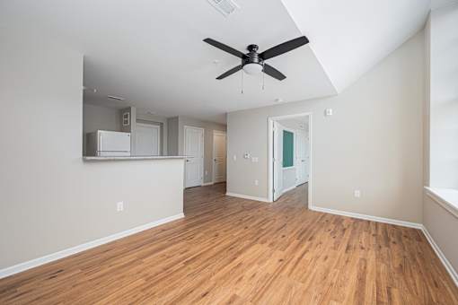 A room with a ceiling fan and wooden flooring.