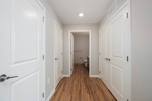 A hallway with white doors and a wooden floor.