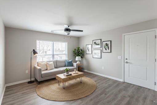 A living room with a couch, a table, and a ceiling fan.