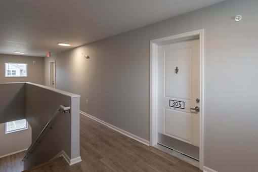 A room with a door labeled 305 and a staircase leading to the upper floor.