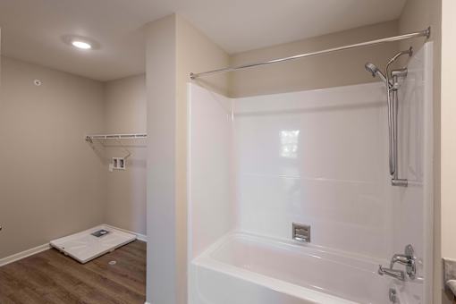 A white bathroom with a walk-in shower and a toilet mat on the floor.