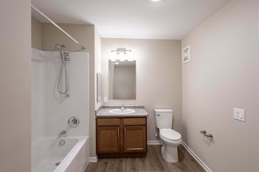 A small bathroom with a white tub, sink, and toilet.