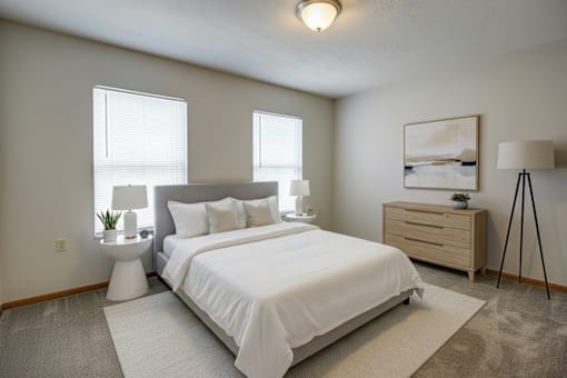 A bedroom with a large bed, nightstand, and lamp.