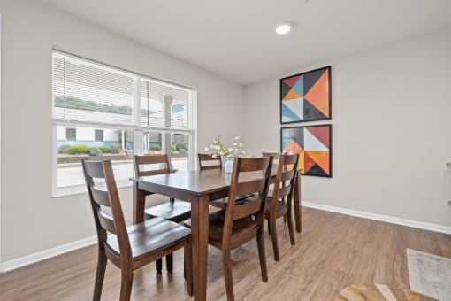 a dining room with a wooden table and chairs and a large window