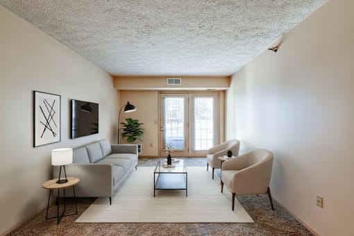 A living room with a grey couch, a white table, and a plant.