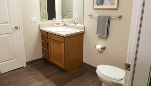 A bathroom with a white toilet and a wooden cabinet.