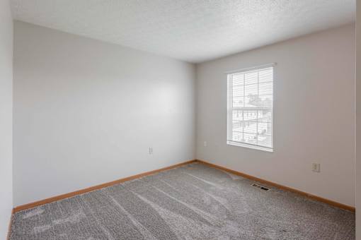 A room with a carpeted floor and a window.