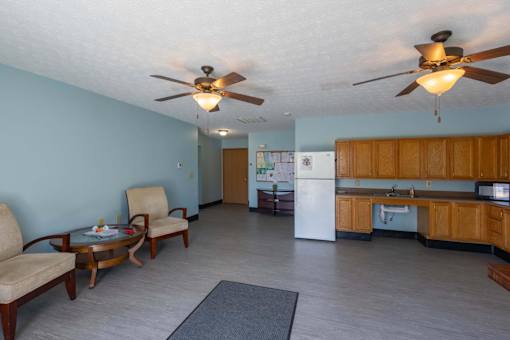 A living room with a ceiling fan and a dining table with chairs.