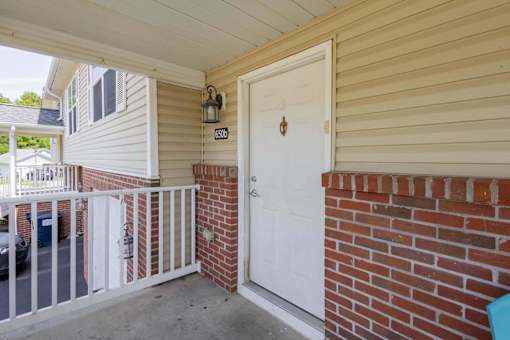 A white door with a gold handle is on a brick wall.