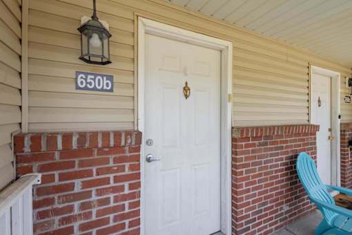 A white door with a black lantern above it and a number 650b on the wall.