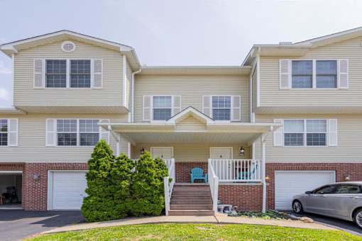 A two-story house with a car parked in front.