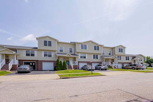 A row of townhouses with cars parked in front.