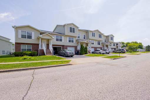 A row of houses with cars parked in front.
