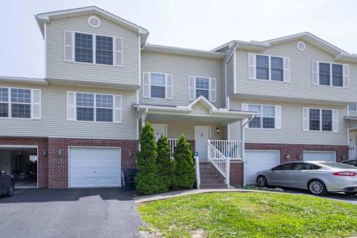 A two-story house with a garage and a car parked in front.