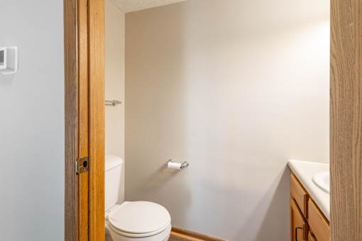 A white toilet is in a small bathroom with a wooden door.