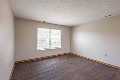 A room with a window and wooden flooring.