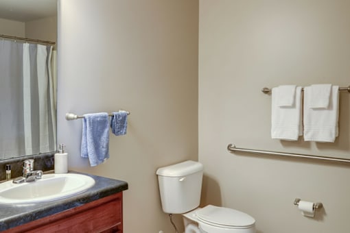 A bathroom with a toilet, sink, and towels.