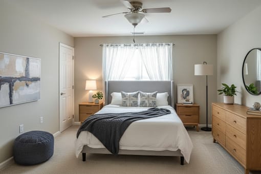 A bedroom with a large bed, a ceiling fan, and a painting on the wall.