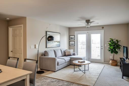 A living room with a grey couch, a coffee table, and a ceiling fan.