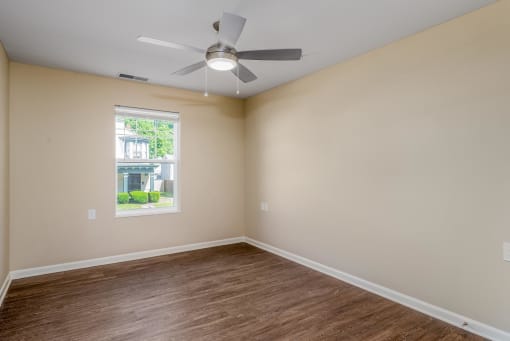an empty room with a ceiling fan and a window
