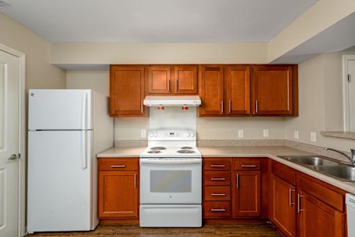 A kitchen with white appliances and wooden cabinets.