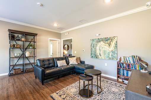 A living room with a black leather couch and a wooden floor.