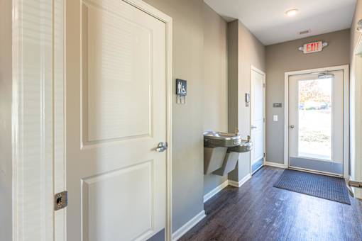 A hallway with a white door and a red exit sign above it.