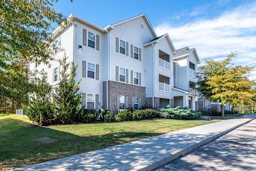A white apartment building with a green lawn in front.