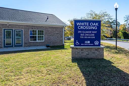 A sign for White Oak Crossing stands in front of a building.