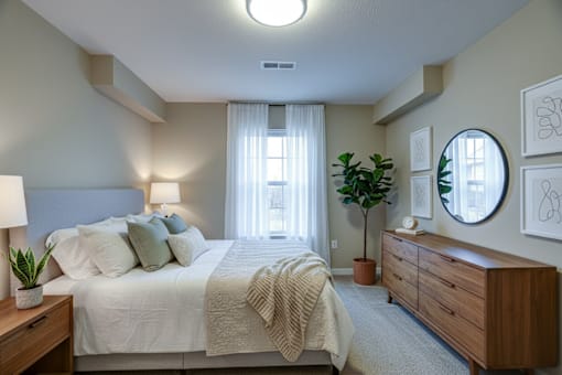 A well-lit bedroom with a large bed and a wooden dresser.