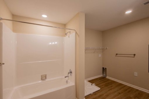 A white bathtub with a shower head and a towel bar.