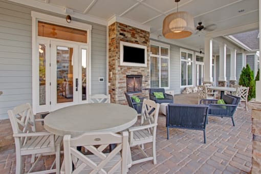 Outdoor Lounge & Entertainment. Chairs, fireplace, tv, windows, and door leading outside. at York Woods at Lake Murray Apartment Homes, South Carolina