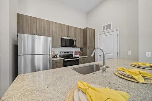 A kitchen with a granite countertop and stainless steel appliances.