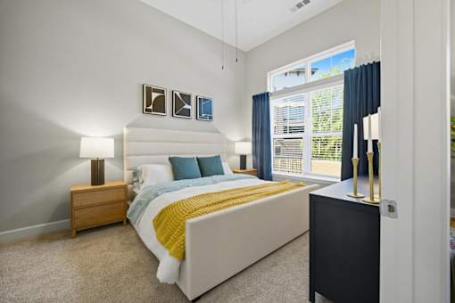 A bedroom with a bed, nightstand, and window.