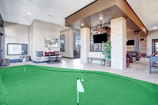 a putting green in the lobby of a clubhouse with a tv