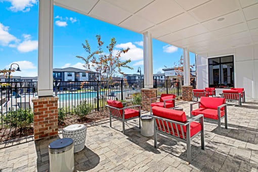 a covered patio with red chairs and tables and a pool