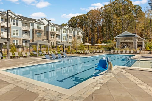 a swimming pool with chairs around it in front of an apartment building
