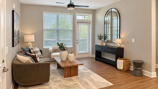 A living room with a brown couch, a coffee table, and a large mirror.