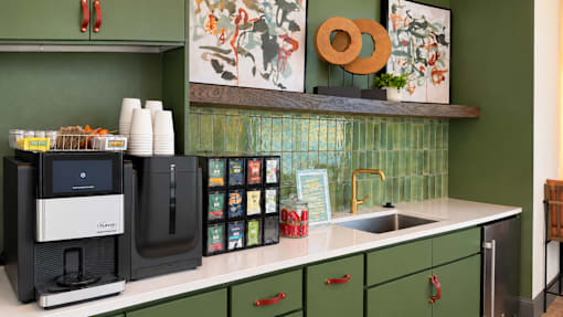 A kitchen with green cabinets and a black coffee maker.
