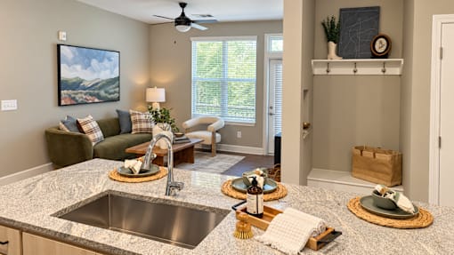 A kitchen with a marble countertop and a painting of a mountain scene on the wall.