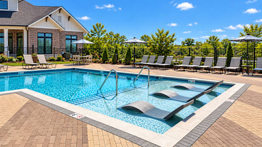 A pool with a brick border and a black metal fence.