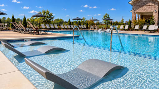 A large swimming pool with a diving board and sun loungers.