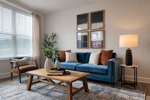A living room with a blue couch, a wooden coffee table, and a lamp.