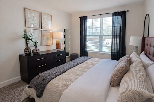 A bedroom with a large bed and a window with black curtains.
